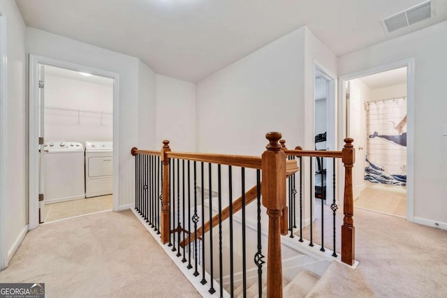 corridor with separate washer and dryer and light carpet