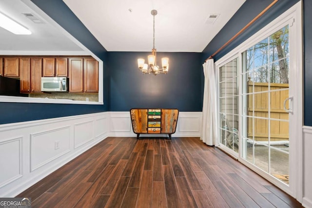 unfurnished dining area featuring dark hardwood / wood-style flooring and an inviting chandelier