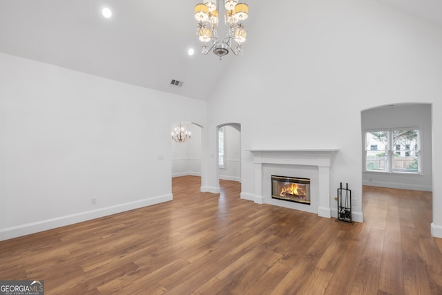 unfurnished living room with hardwood / wood-style floors, a notable chandelier, and high vaulted ceiling