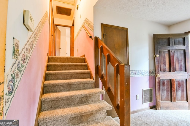 stairway featuring a textured ceiling