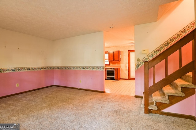 carpeted spare room featuring beverage cooler and a textured ceiling