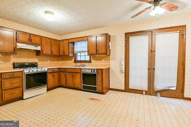 kitchen with dishwasher, sink, ceiling fan, gas range oven, and a textured ceiling