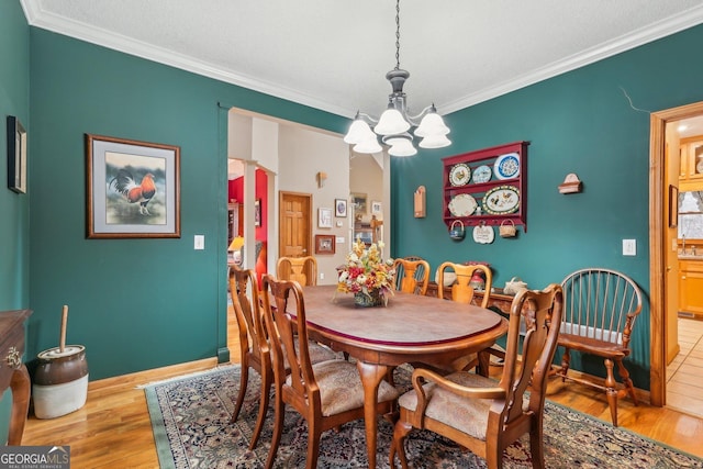 dining area featuring baseboards, ornamental molding, light wood-type flooring, and a notable chandelier