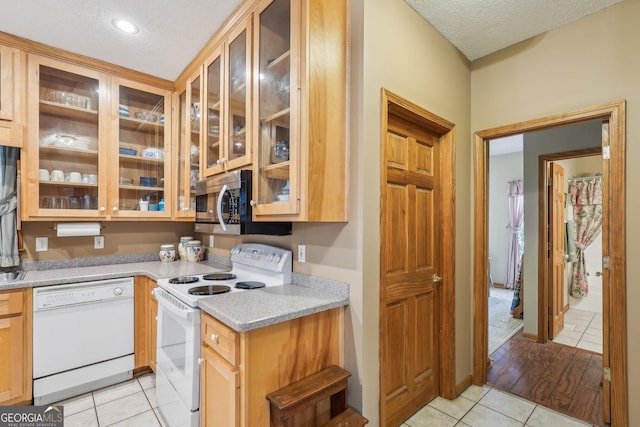 kitchen with white appliances, light stone countertops, a textured ceiling, and light tile patterned floors