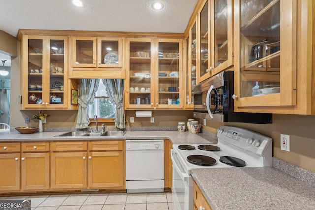 kitchen featuring white appliances, a sink, and glass insert cabinets