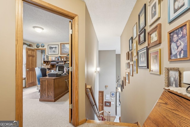 hallway with light colored carpet and a textured ceiling