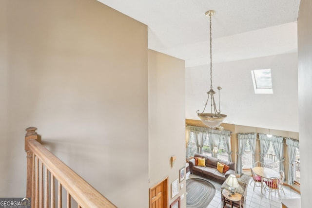 hallway with high vaulted ceiling and a skylight