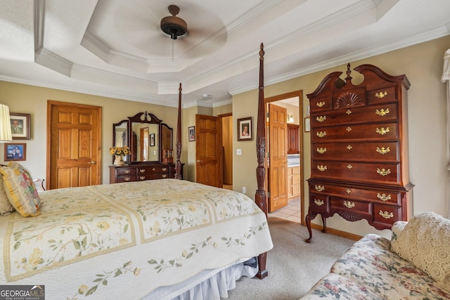 carpeted bedroom featuring ensuite bath, ornamental molding, and a tray ceiling