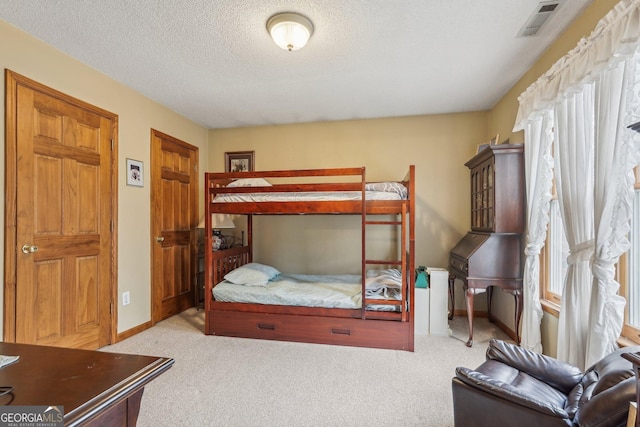 bedroom featuring light carpet, visible vents, baseboards, and a textured ceiling