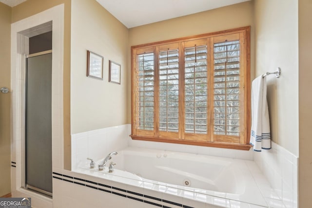 bathroom featuring a stall shower and a bath