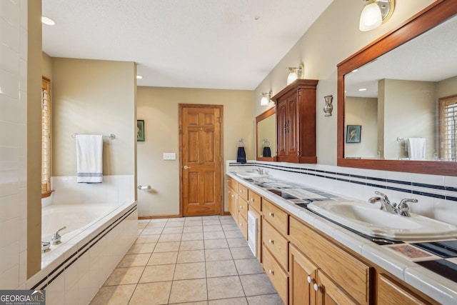 full bathroom with a bath, tile patterned flooring, double vanity, and a sink