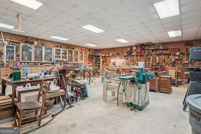 interior space featuring a workshop area, a drop ceiling, and unfinished concrete floors