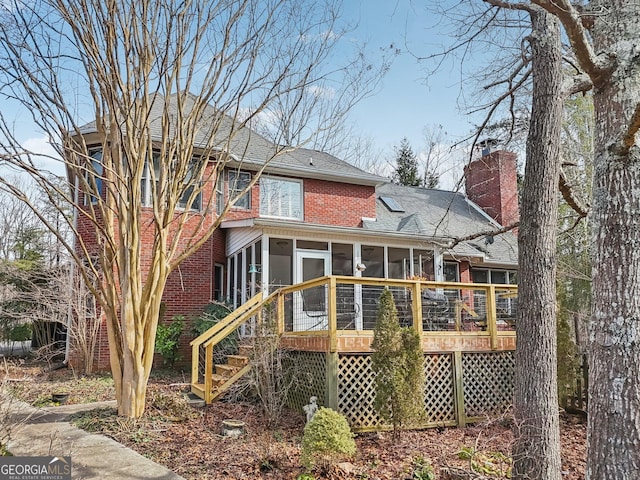 back of house with brick siding, stairway, a chimney, and a sunroom