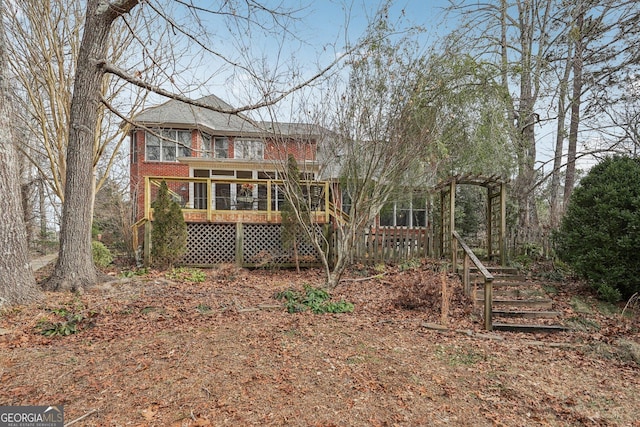 rear view of house with brick siding and a sunroom