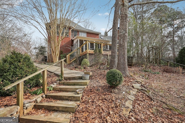 view of front of home with a sunroom, brick siding, fence, and stairs