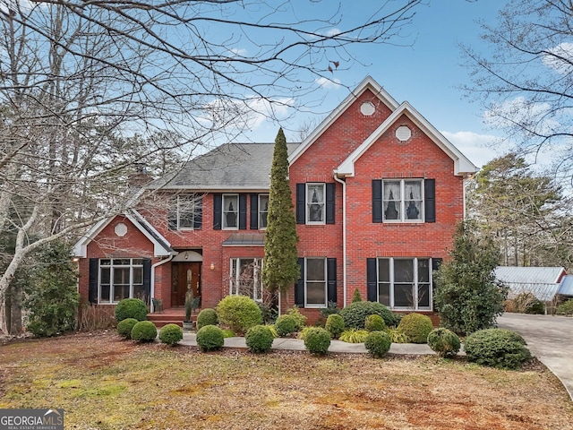 view of front of house featuring a front yard, brick siding, and a chimney