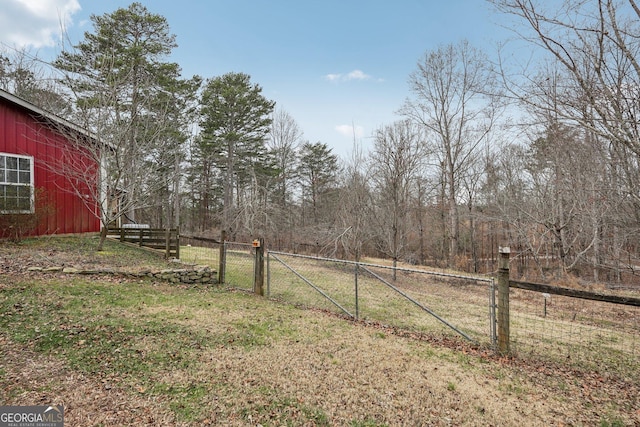 view of yard featuring a pole building, a gate, fence, and an outdoor structure