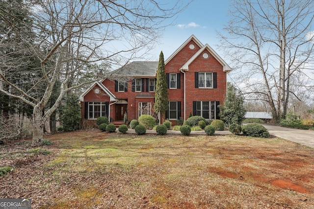 view of front of property featuring brick siding, a chimney, and a front lawn