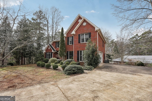 view of front of home with a garage, concrete driveway, brick siding, and central air condition unit