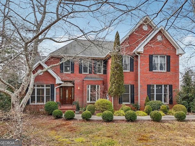 view of front of home featuring brick siding, a chimney, and a front lawn