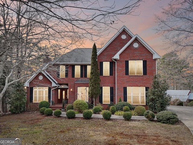 view of front of property with a yard, brick siding, and a chimney