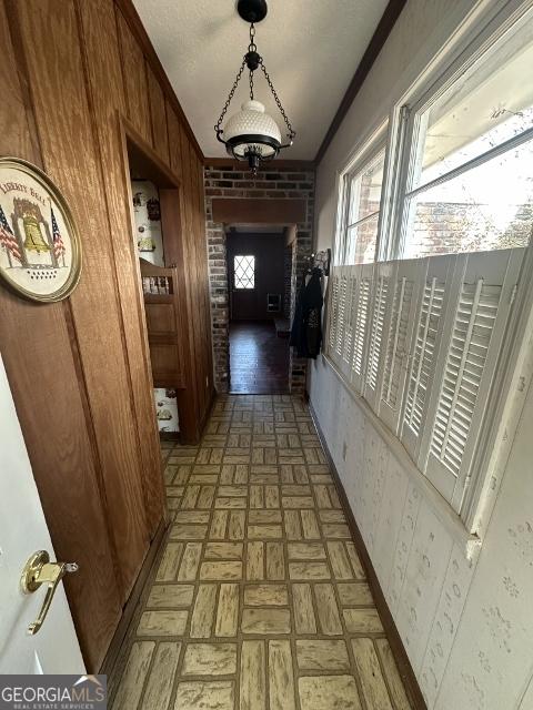 corridor featuring crown molding and wood walls