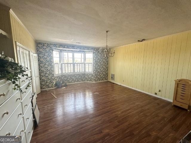 empty room with an inviting chandelier, dark wood-type flooring, and a textured ceiling