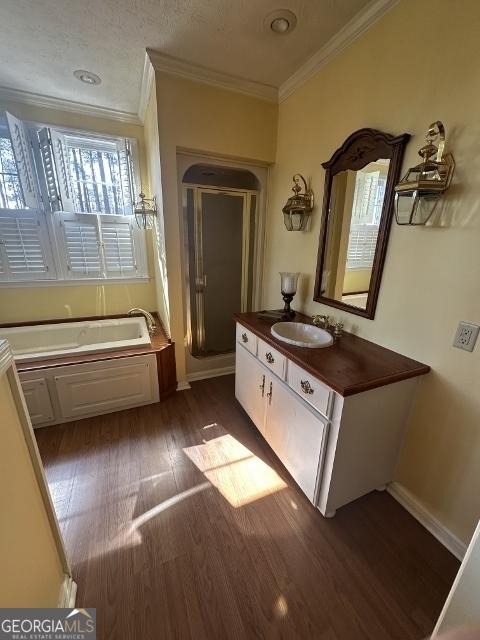 bathroom featuring hardwood / wood-style flooring, shower with separate bathtub, vanity, and crown molding