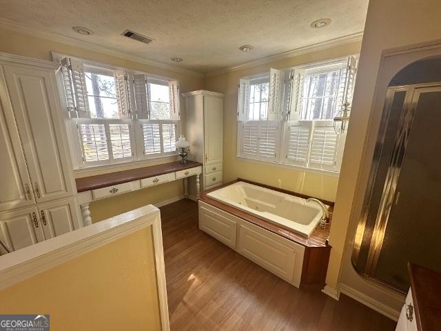 bathroom featuring hardwood / wood-style flooring, ornamental molding, a bath, and a textured ceiling