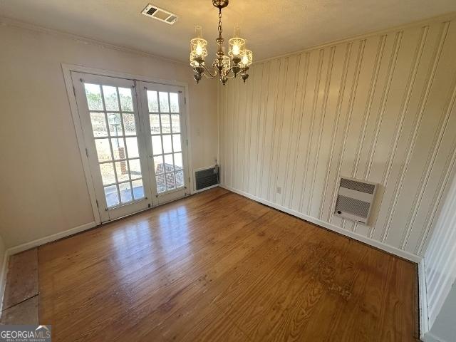 empty room featuring an inviting chandelier and hardwood / wood-style floors