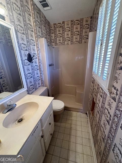 bathroom with vanity, tile patterned flooring, toilet, and walk in shower