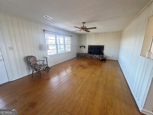 unfurnished living room with hardwood / wood-style floors, a fireplace, and ceiling fan