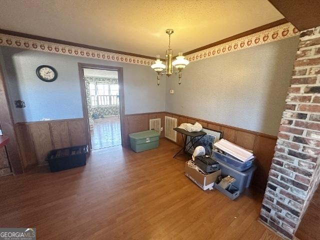 dining area featuring crown molding, a notable chandelier, hardwood / wood-style flooring, and wooden walls