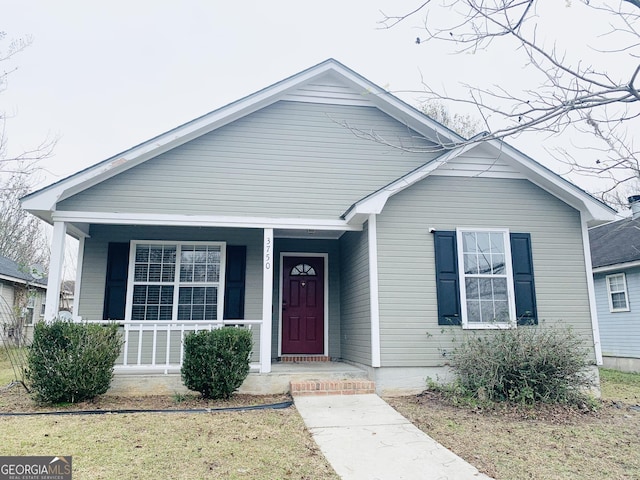 bungalow-style home with a front yard and covered porch