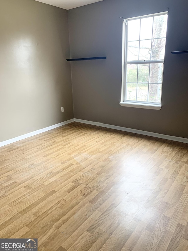 spare room featuring baseboards and wood finished floors