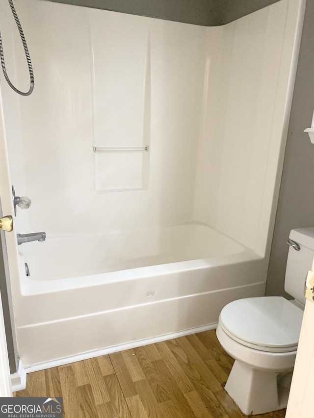 bathroom featuring wood finished floors, toilet, and  shower combination