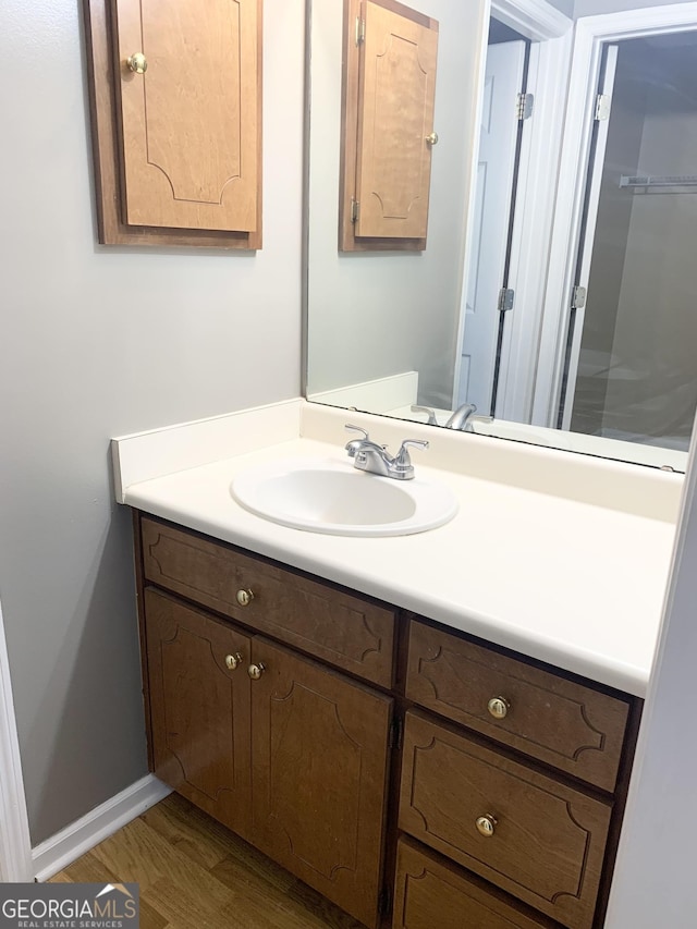 bathroom with wood finished floors, vanity, and baseboards
