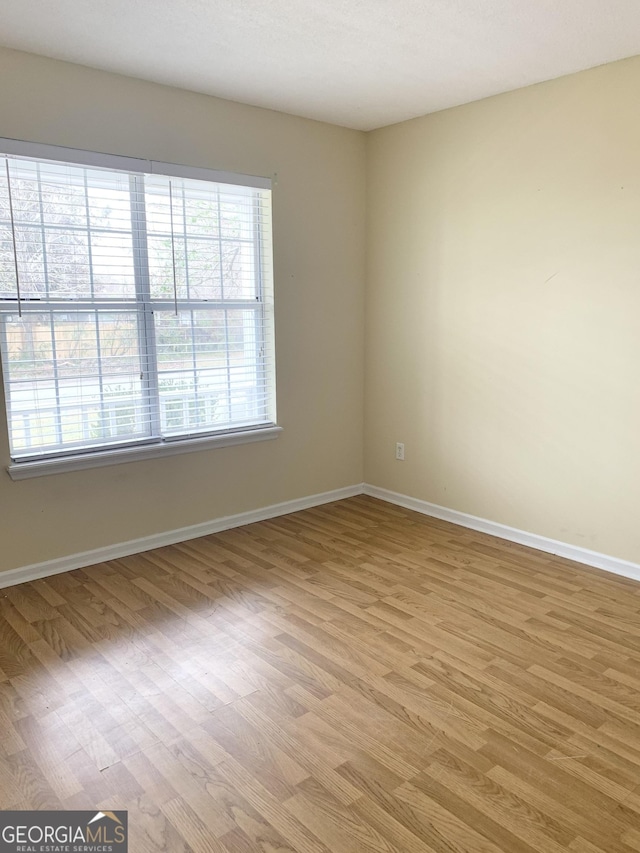 spare room featuring baseboards and light wood-type flooring