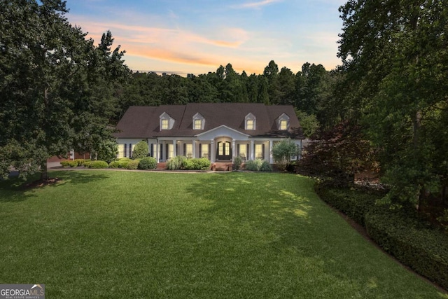 cape cod home featuring a yard