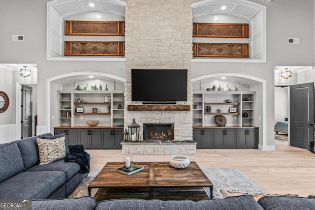 living room with built in shelves, a fireplace, hardwood / wood-style floors, and a high ceiling