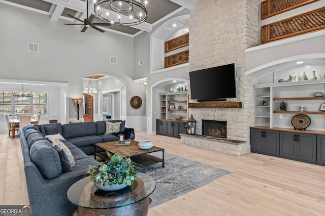 living room featuring built in shelves, a fireplace, beamed ceiling, and light wood-type flooring