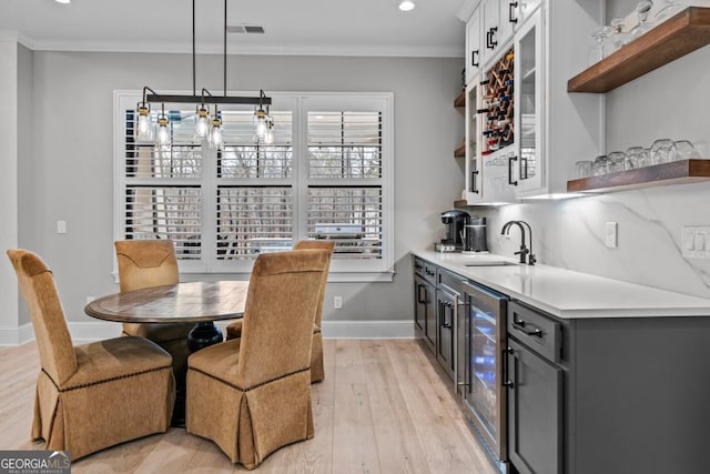 kitchen with sink, gray cabinetry, white cabinetry, crown molding, and hanging light fixtures