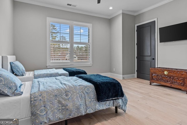 bedroom featuring crown molding and light hardwood / wood-style flooring