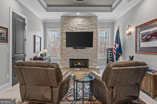 living room featuring a tray ceiling, a fireplace, ornamental molding, and light wood-type flooring