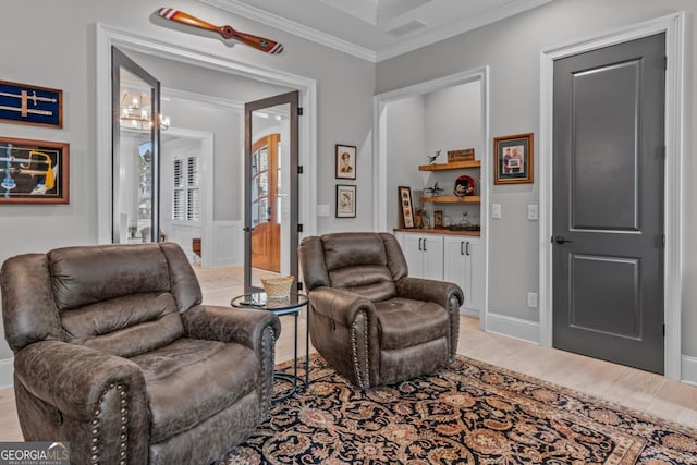 sitting room with ornamental molding and light wood-type flooring