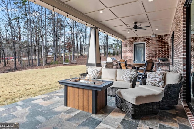 view of patio / terrace with exterior kitchen, ceiling fan, and an outdoor fire pit