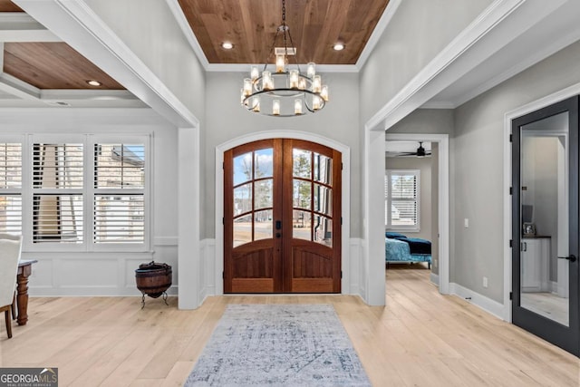 entrance foyer featuring french doors, ornamental molding, wood ceiling, an inviting chandelier, and light hardwood / wood-style flooring