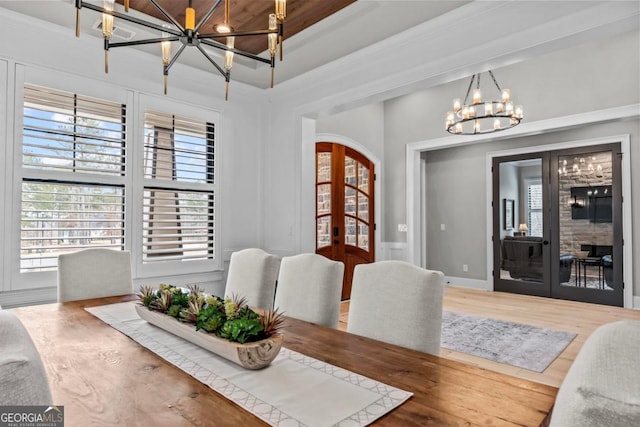 dining room with wood-type flooring, ornamental molding, a notable chandelier, and french doors