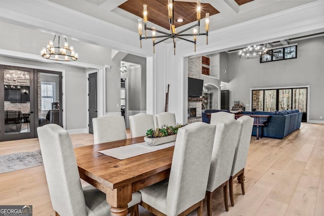 dining room with beam ceiling, coffered ceiling, a fireplace, and light hardwood / wood-style floors