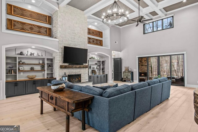 living room featuring coffered ceiling, wood-type flooring, a stone fireplace, and a high ceiling